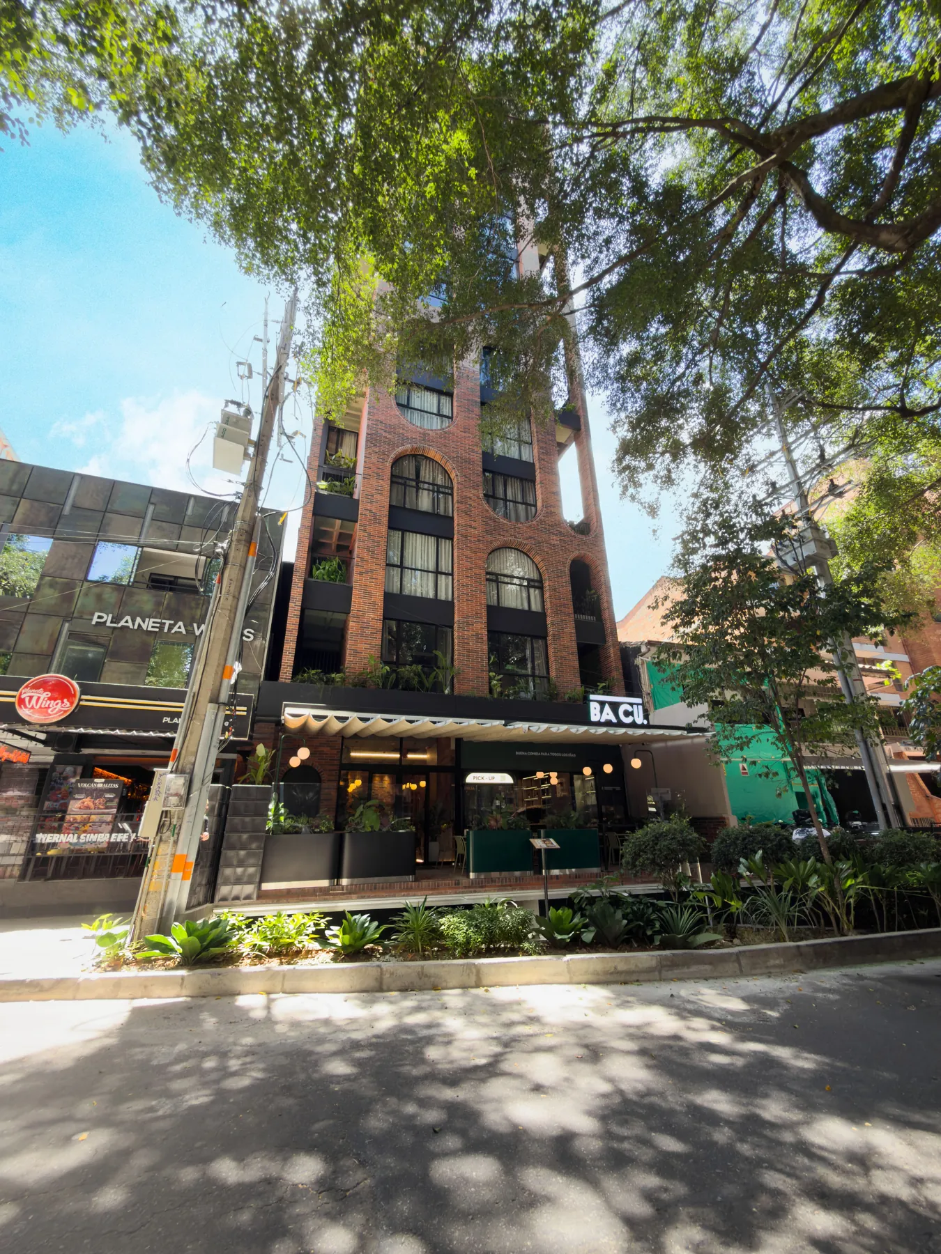 Fachada do URBIT Garden entre árvores em Laureles, Medellín
